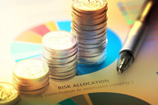 Coins on risk allocation chart Paper with risk allocation pie chart with increasing stacks of coins and pen