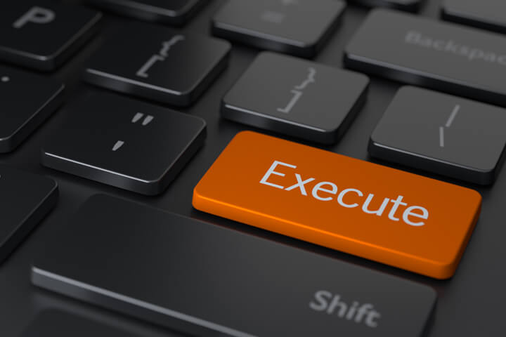 Dark computer keyboard with large orange Execute key concept for buying stocks online