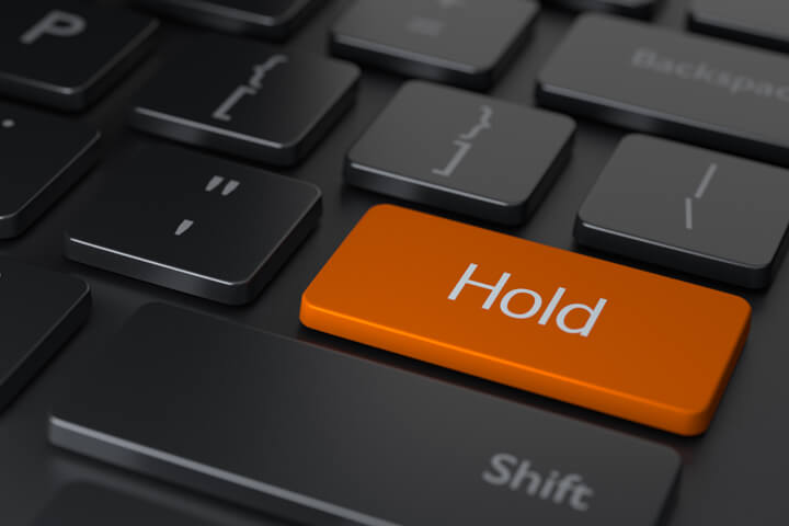 Dark computer keyboard with large orange Hold key representing holding an investment rather than selling
