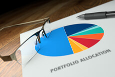 Portfolio allocation pie chart Paper on desk showing pie chart of portfolio allocation with reading glasses and ballpoint pen