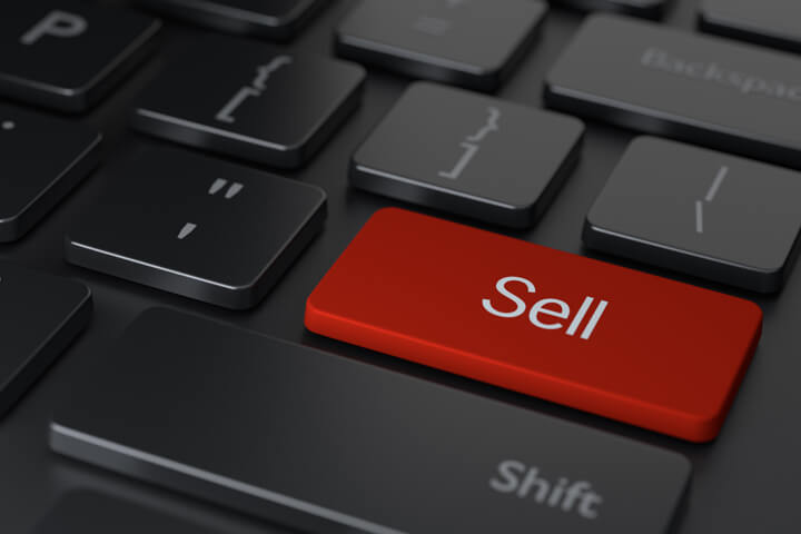 Dark laptop keyboard with red Sell key representing stock or asset sale