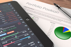 Desk with investment pie chart and iPad showing stock pricing information