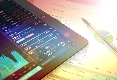iPad with stock charts iPad on table showing stock trading data with pen and pie chart on paper