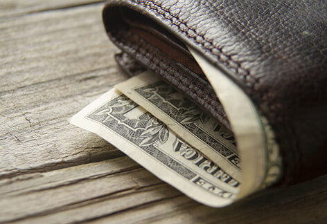 Wallet with one dollar bills Leather wallet with dollar bills sticking out on wood background