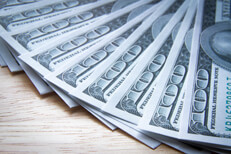 Fanned out $100 bills on wood table $100 bills evenly fanned out on wood table