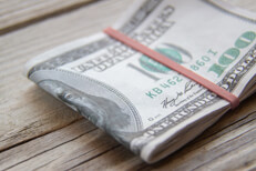 Folded $100 bills on wood $100 bills folded with rubber band on weathered wood background