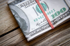 Folded $100 bills top view $100 bills folded with rubber band on weathered wood background top view