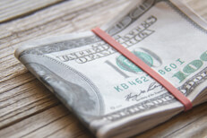 $100 bills folded with rubber band $100 bills folded with rubber band on weathered wood background