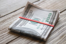 Folded bundle of $100 bills $100 bills folded with rubber band on weathered wood planks