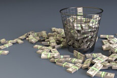 Money thrown in trash can Bundles of U.S. currency in trash can concept for waste or throwing money away