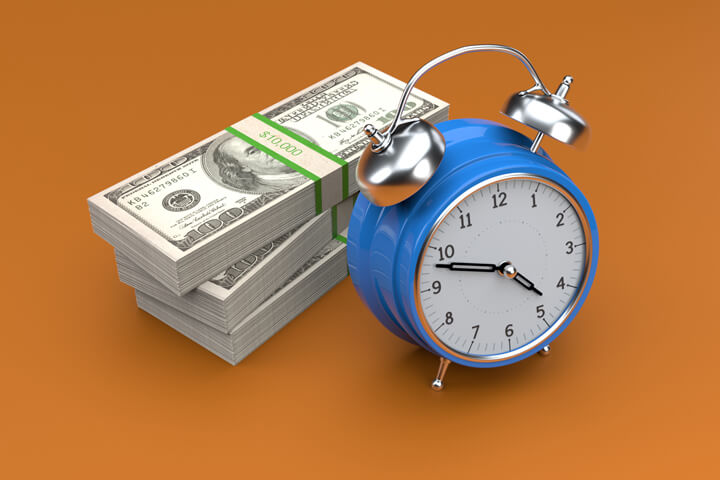 Concept photo of blue clock and stacks of U.S. cash on orange background