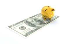 Gold piggy bank sitting on one 100 dollar U.S. bill concept image