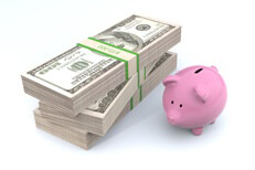 Concept image of small pink piggy bank next to large stack of U.S. 100 dollar bills