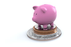Pink piggy bank standing on stack of U.S. coins