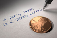 Penny saved is earned U.S. penny on paper with pen writing A penny saved is a penny earned