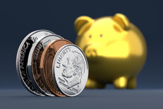 U.S. coins standing on edge in foreground with blurred gold piggy bank in background