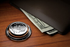 Coins and wallet Stack of U.S. coins with wallet and protruding bills on wood table