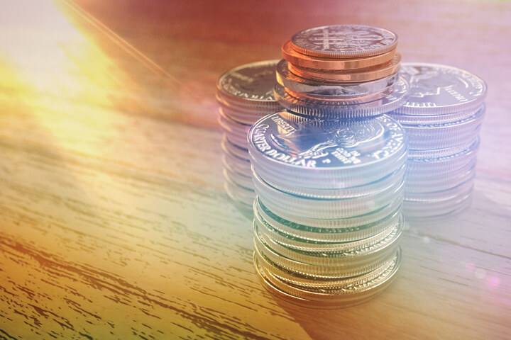 Three large stacks of shiny quarters with other smaller coins on top with corner light flare and overlay effect