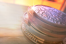 Coins stacked on wood flare Stack of U.S. coins with light flare on wood at angle with sunlight in window in the background