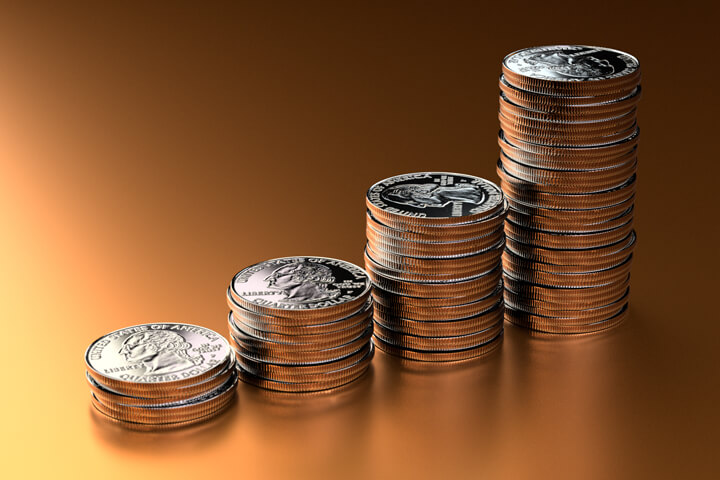 Increasing stacks of U.S. quarters on orange background with left light