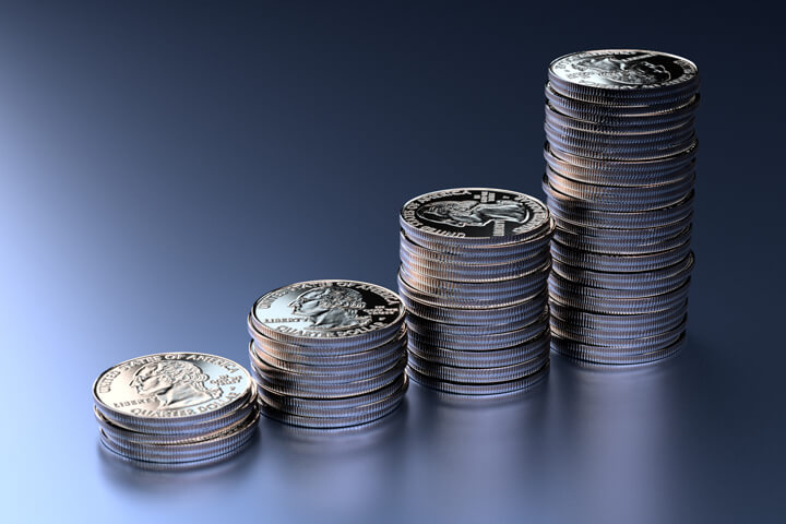 Increasing stacks of U.S. quarters on blue background with left light