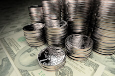 Many stacks of U.S. quarters of different height on one hundred dollar bills