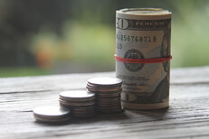 Stacks of coins and roll of bills Increasing stacks of quarter coins with roll of bills as last column
