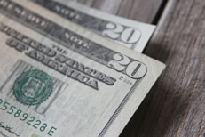 Two slightly curved twenty dollar bills on wood plank background