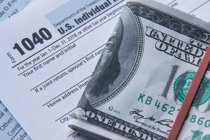 Folded 100 dollar bills on IRS tax form 1040