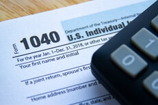 1040 tax form with calculator Photo showing 1040 IRS tax form and corner of calculator on desk