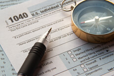 1040 form with compass and pen IRS 1040 form with navigation compass and ballpoint pen concept for tax help or directions