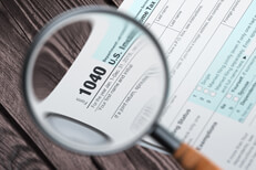 Tax 1040 magnifying glass IRS form 1040 magnified in magnifying glass on wood plank background