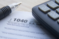 IRS form 1040 with pen and calculator Close up photo of IRS form 1040 with calculator and ballpoint pen on desk