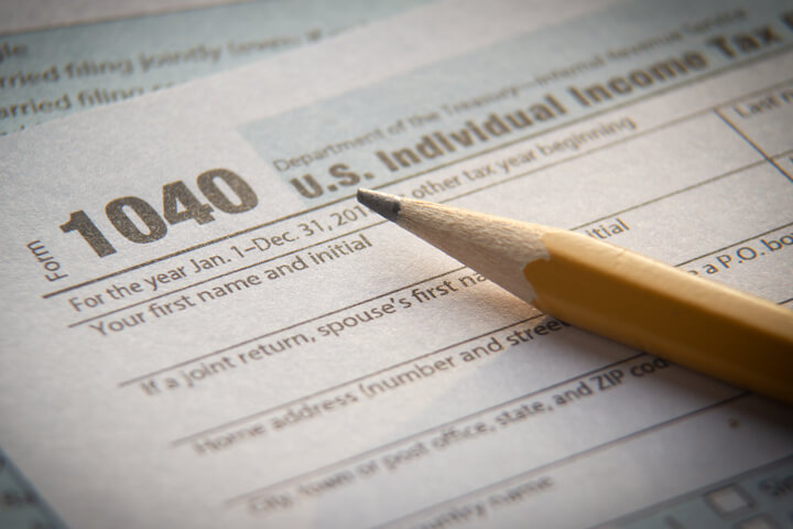 Yellow pencil lying on IRS form 1040 with vignette