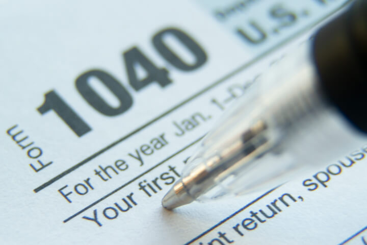 Extreme close up photo of tip of pen in the first name field of IRS 1040 tax form