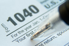 Form 1040 First Name Extreme close up photo of tip of pen in the first name field of IRS 1040 tax form