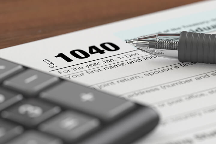 IRS form 1040 with ballpoint pen and calculator blurred with camera depth of field