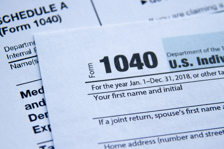 Top view photo of IRS 1040 tax form with Schedule A form behind