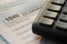 Tax paperwork in sun Sunrise lighting tax 1040 form with corner of calculator