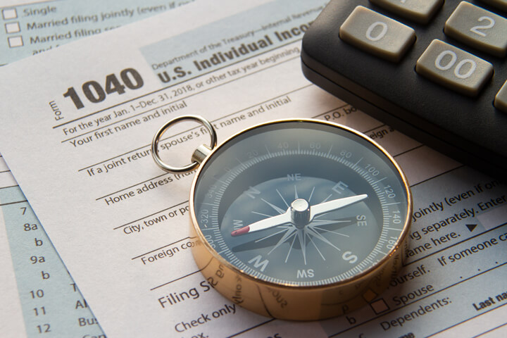 Navigational compass and calculator on top of IRS form 1040 tax forms