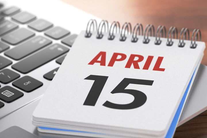 Spiral day calendar showing April 15 lying on laptop concept for tax filing deadline