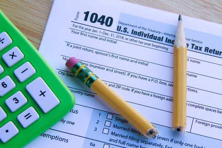 Broken pencil lying on IRS form 1040 on desk with green compact calculator