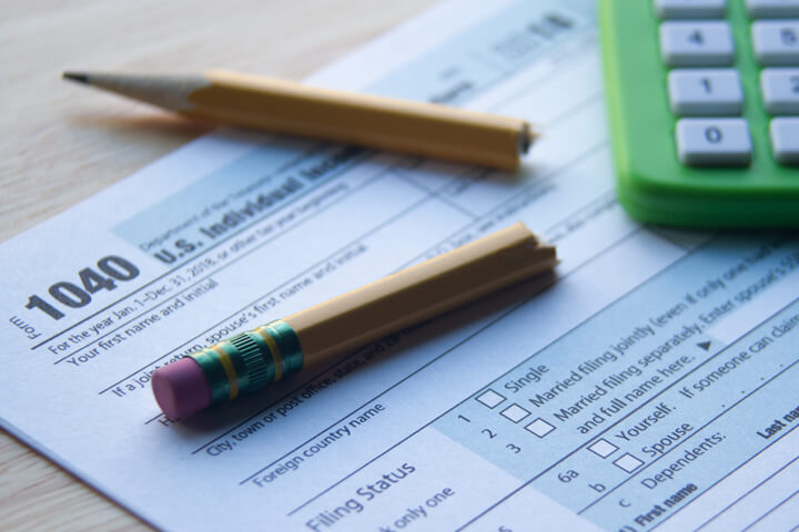 IRS form 1040 with broken pencil and green compact calculator concept for frustrated tax filer