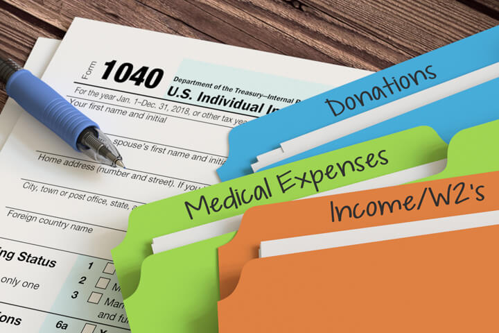 Colorful manila folders for income, expenses, and donations on 1040 tax form