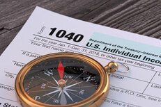 Compass on 1040 tax form Navigational compass lying on IRS form 1040 on word wood plank background