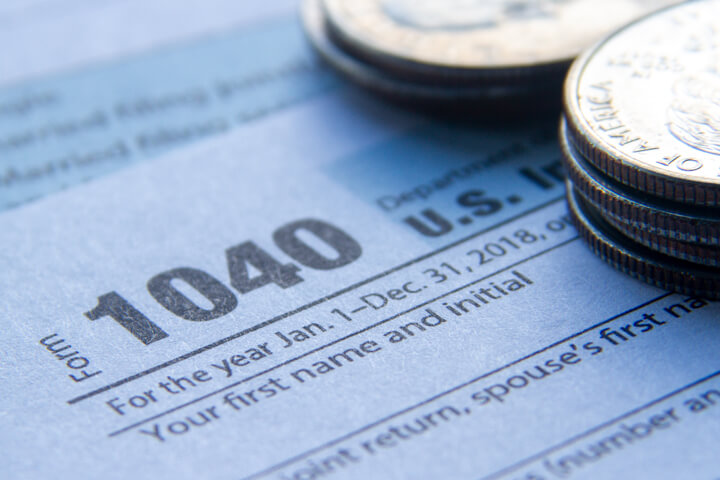 Close up photo of IRS form 1040 with two stacks of U.S. quarters in corner
