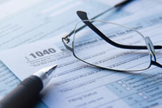 Reading glasses lying on IRS form 1040 with ballpoint pen