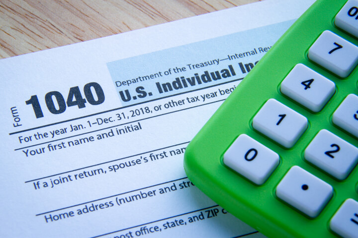 IRS 1040 form with green compact calculator concept photo for filing taxes