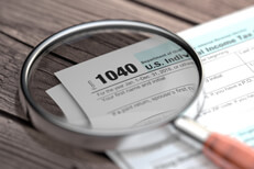 Magnified IRS form 1040 IRS form 1040 lying on worn wood planks with magnifying glass focused on Form 1040 paperwork text
