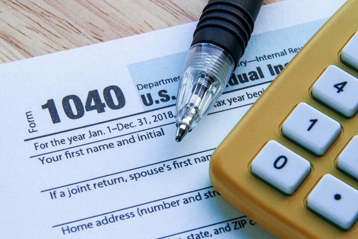 IRS form 1040 with orange calculator and ballpoint pen